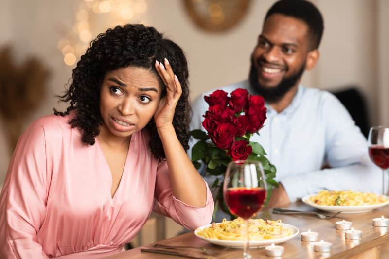 couple on a date woman turned away in disgust at smiling man in background