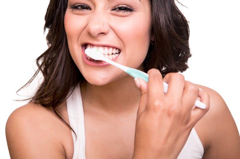 smiling young woman brushing her teeth