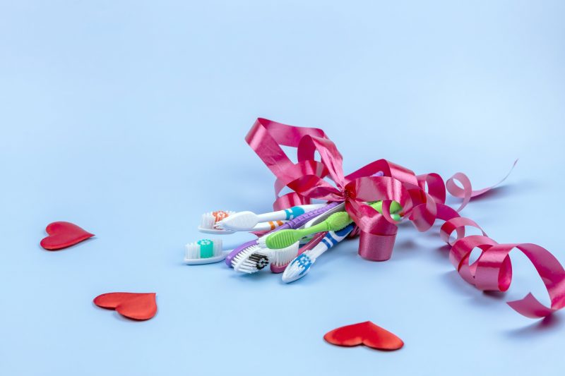 set of toothbrushes tied together with curly ribbon on blue background