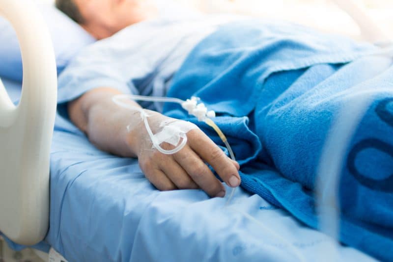 close up of mans hand lying in hospital bed