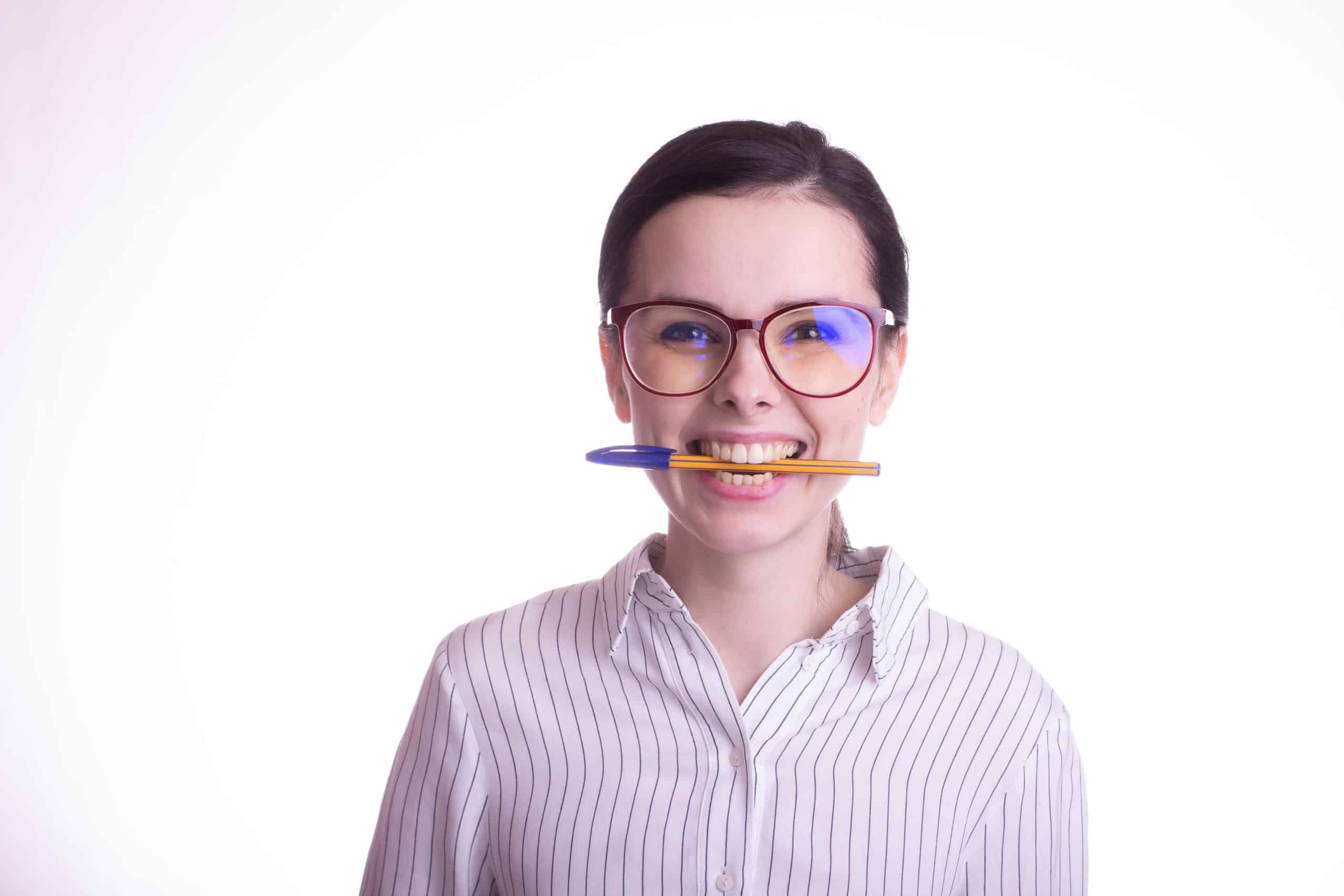 woman smiling with pencil between her teeth