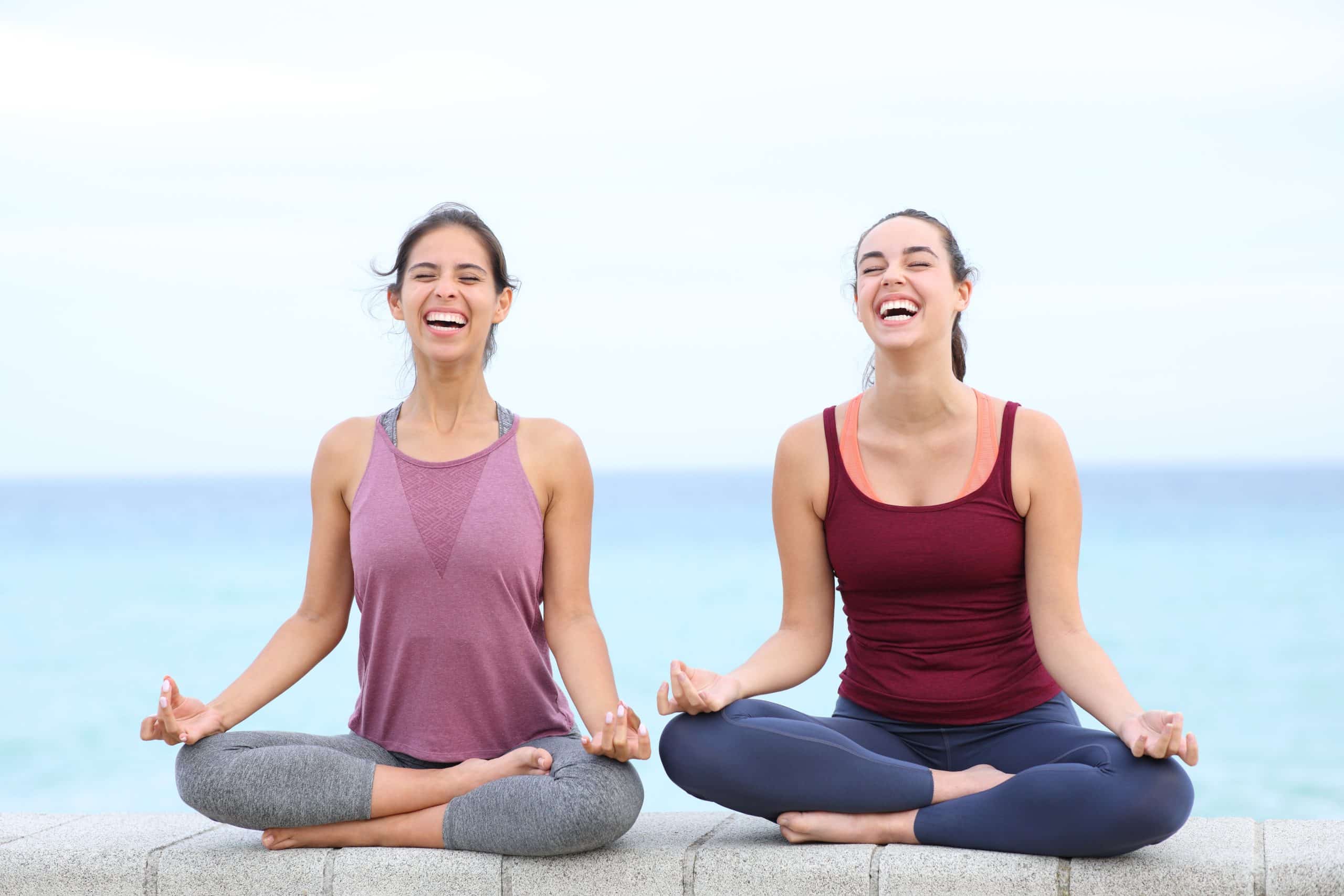 two women laughing while doing yoga