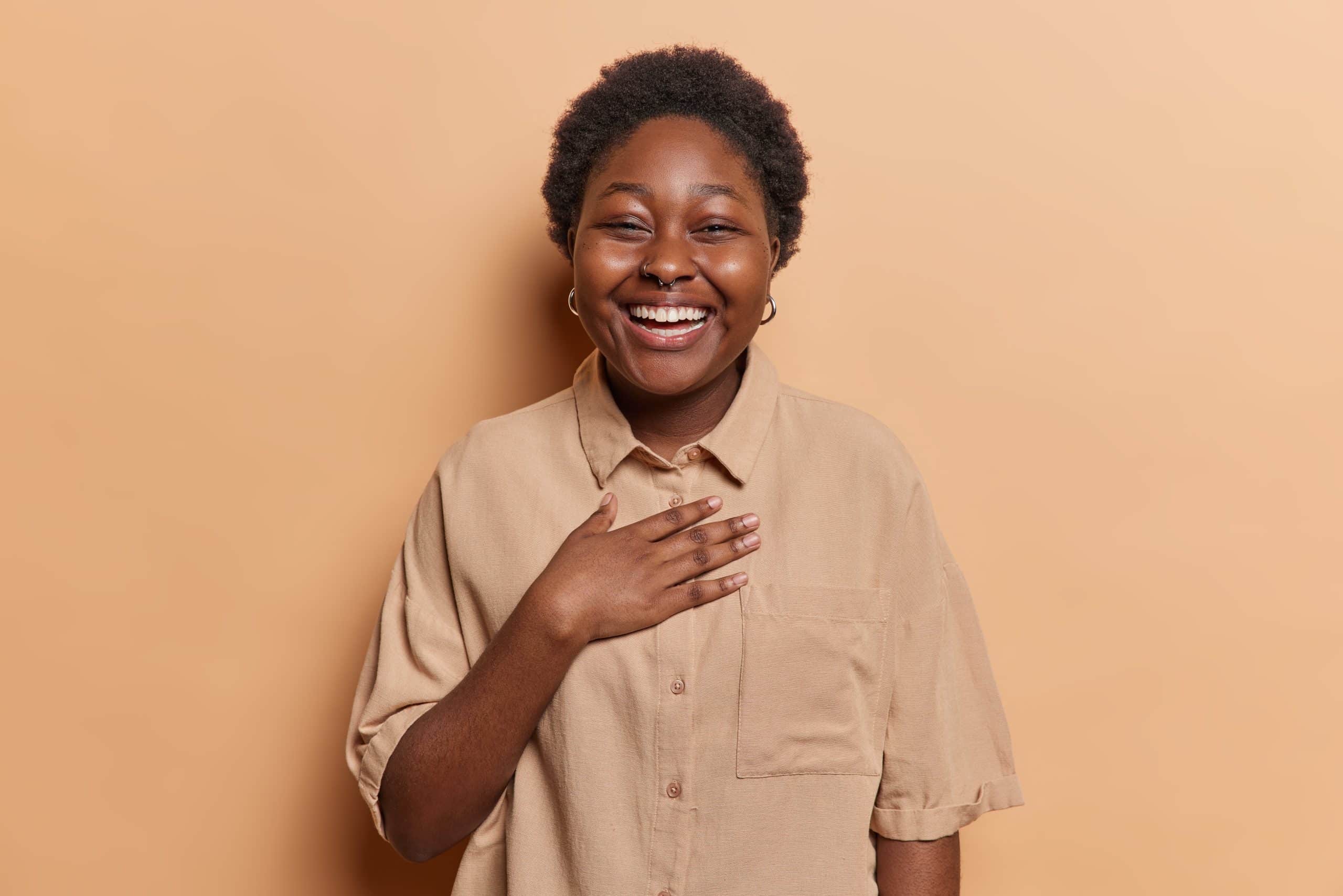 woman with short hair laughing with hand on chest