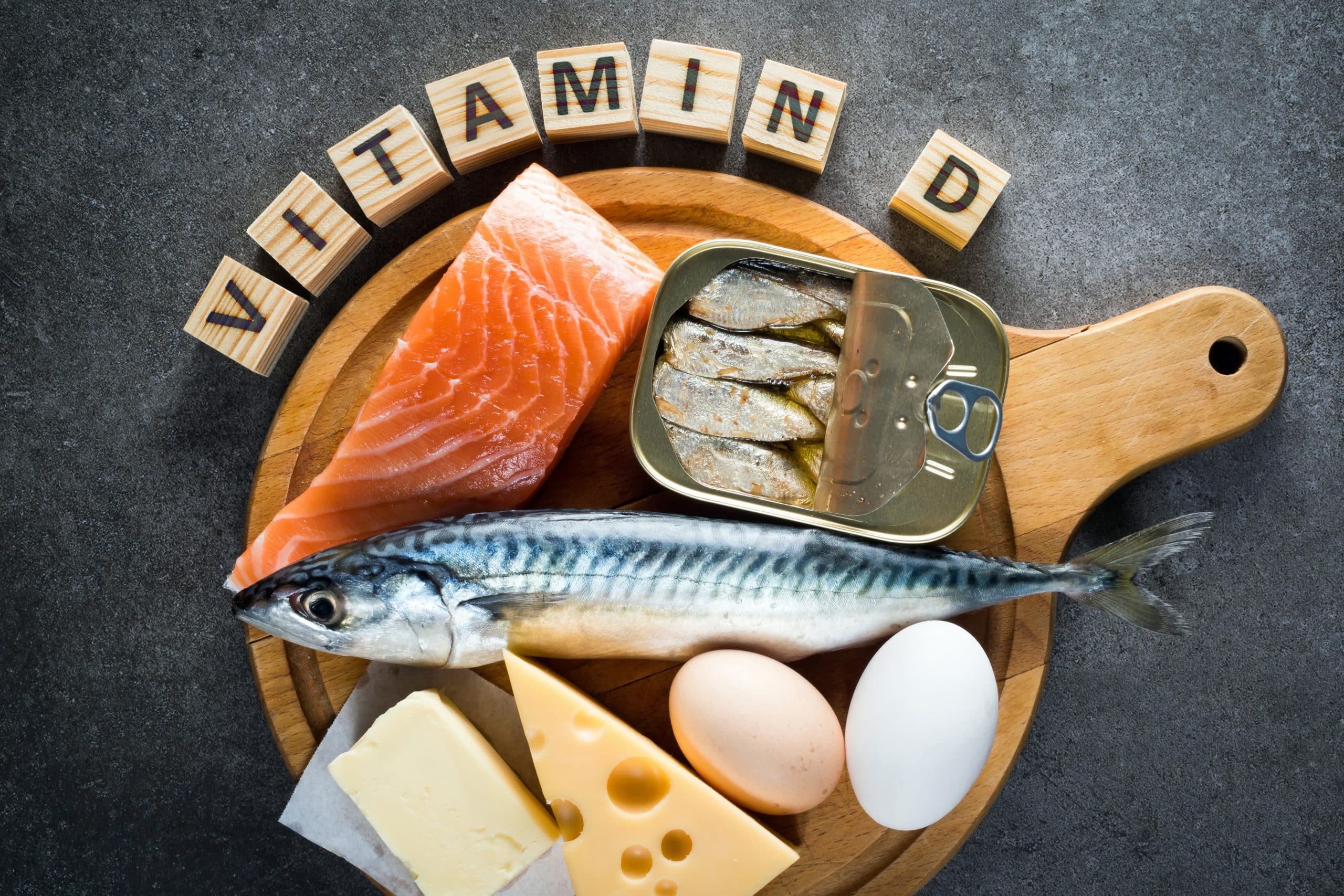 salmon fish eggs and cheese on board with vitamin d spelled in blocks