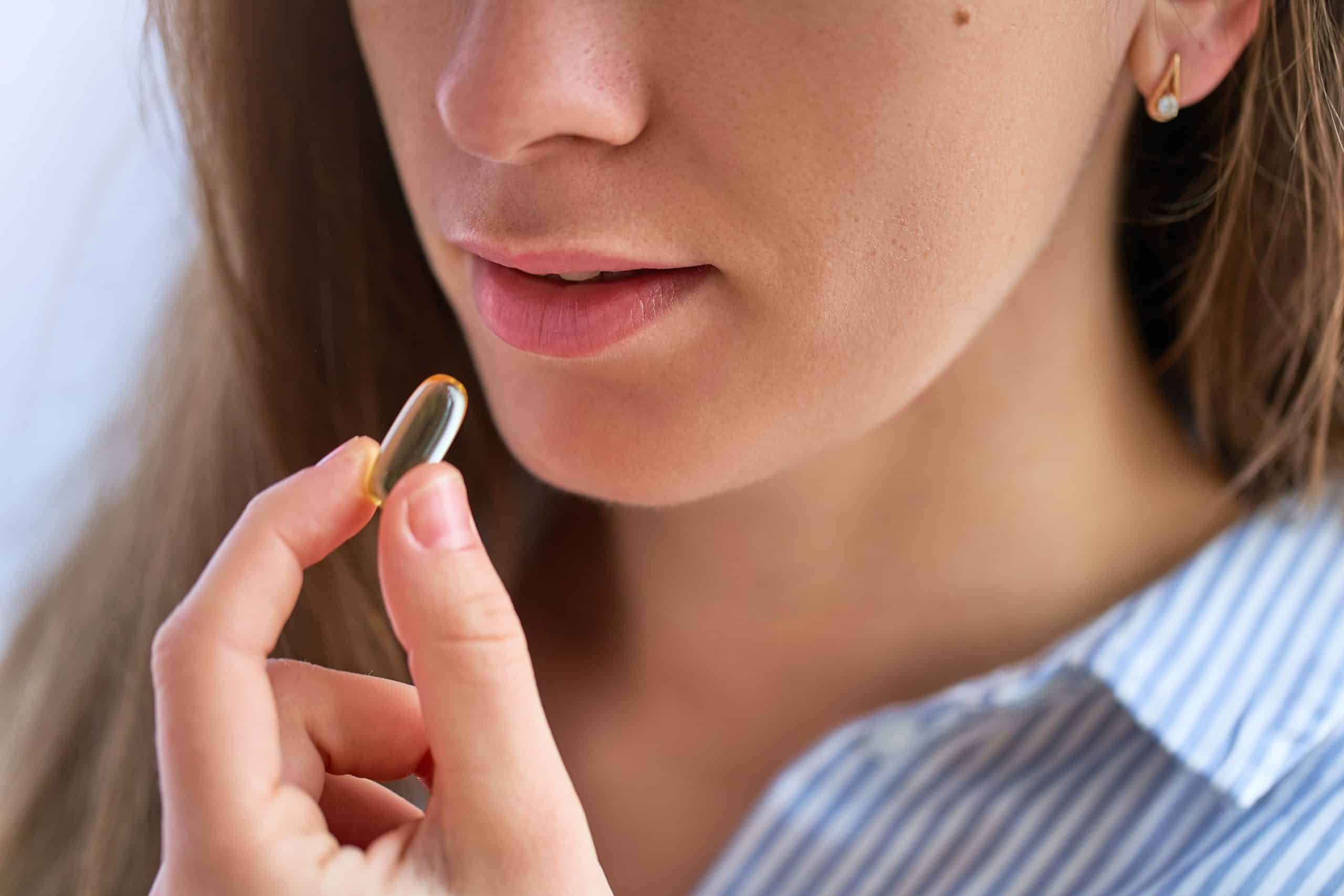 woman holding vitamin capsule to her lips