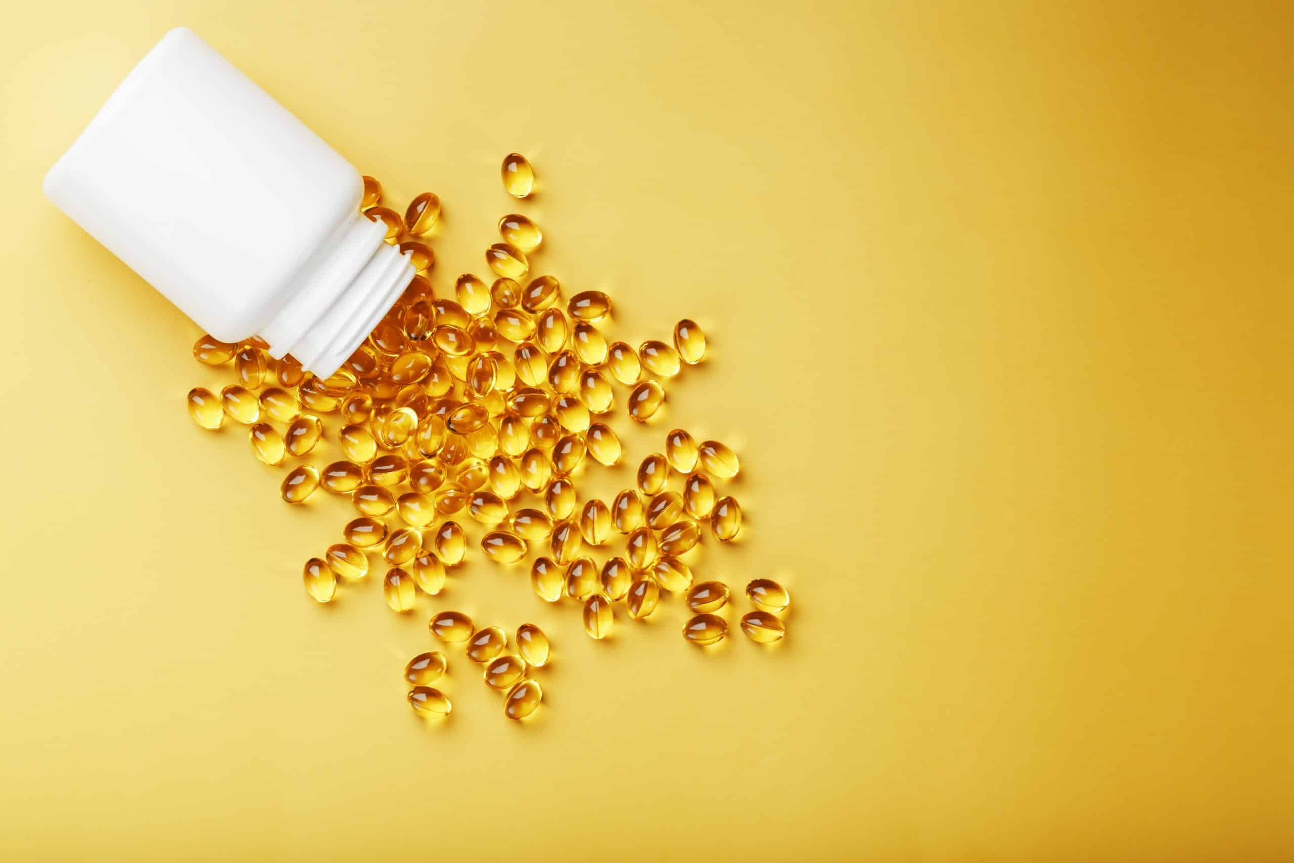 spilled bottle of vitamin d pills on yellow background