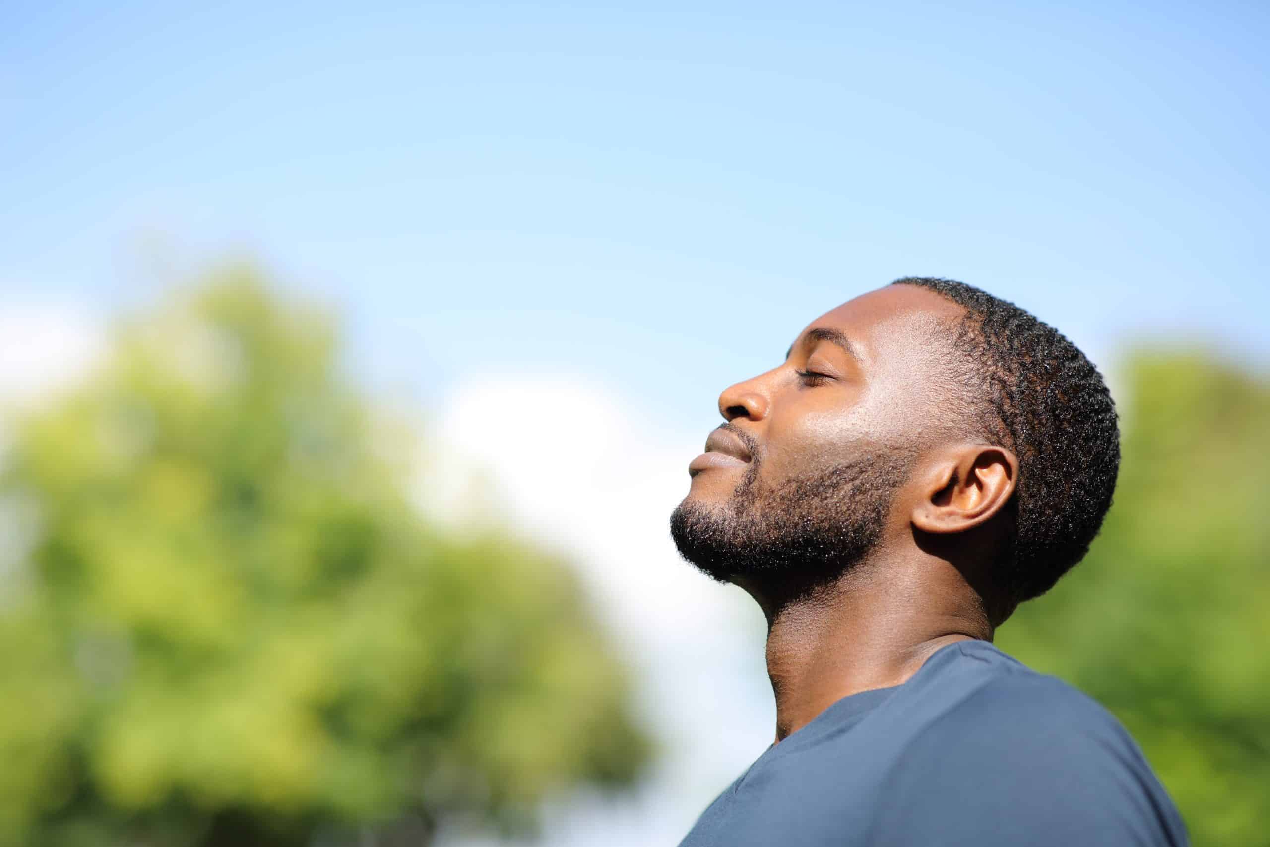 man breathes deeply while looking to the sky