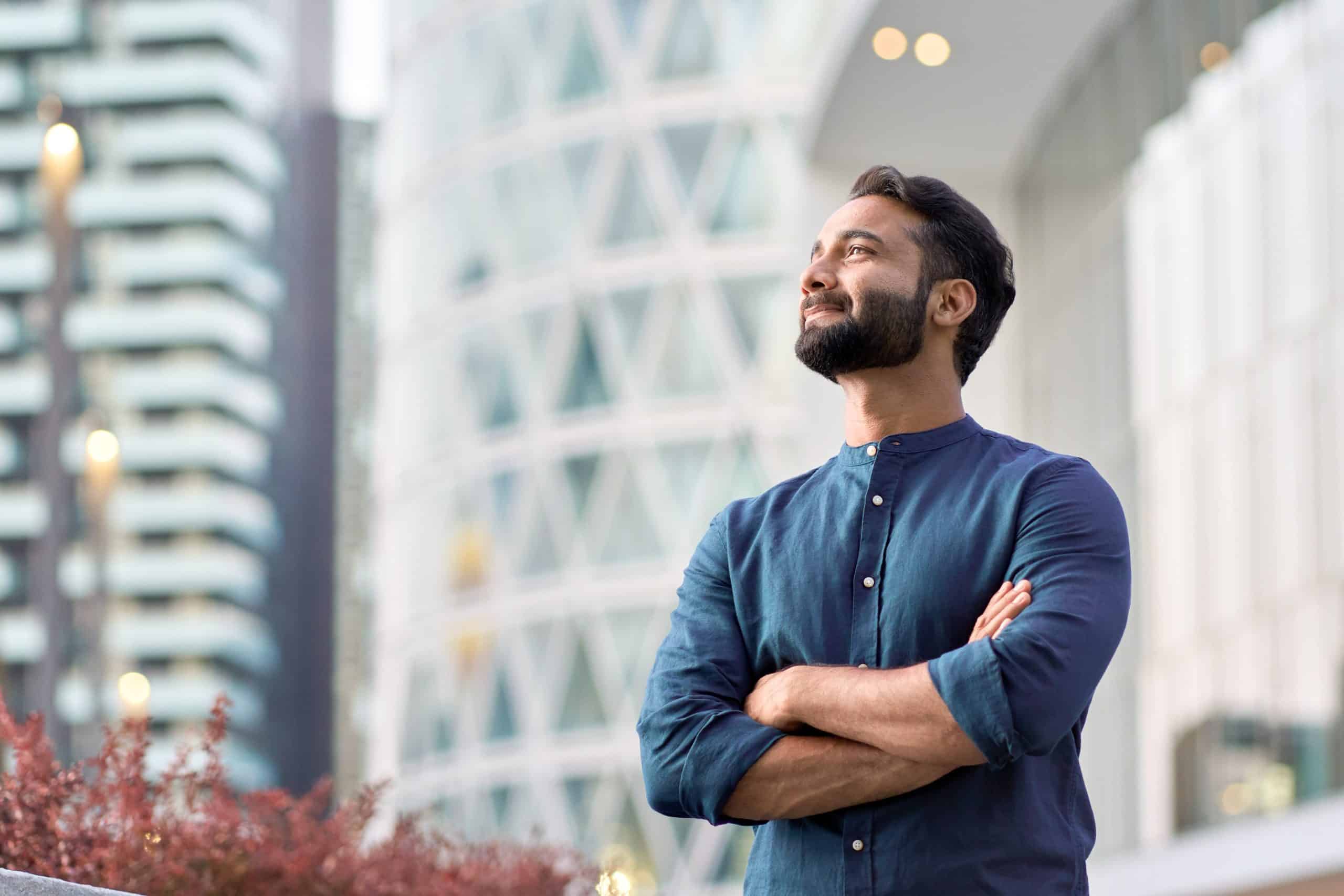 Confident man standing and looking up with his arms folded