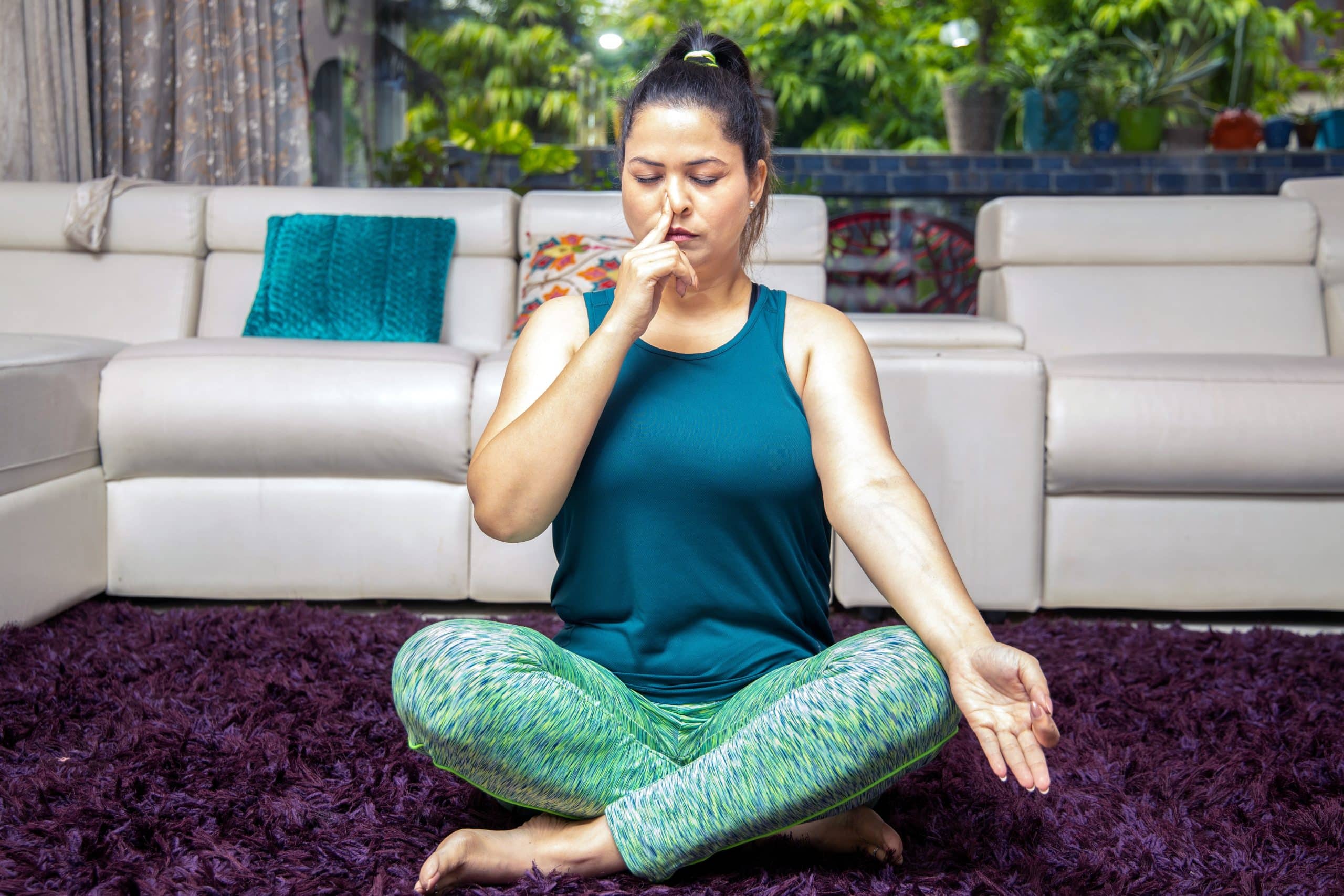 indian woman sits cross legged while practicing alternate nostril breathing