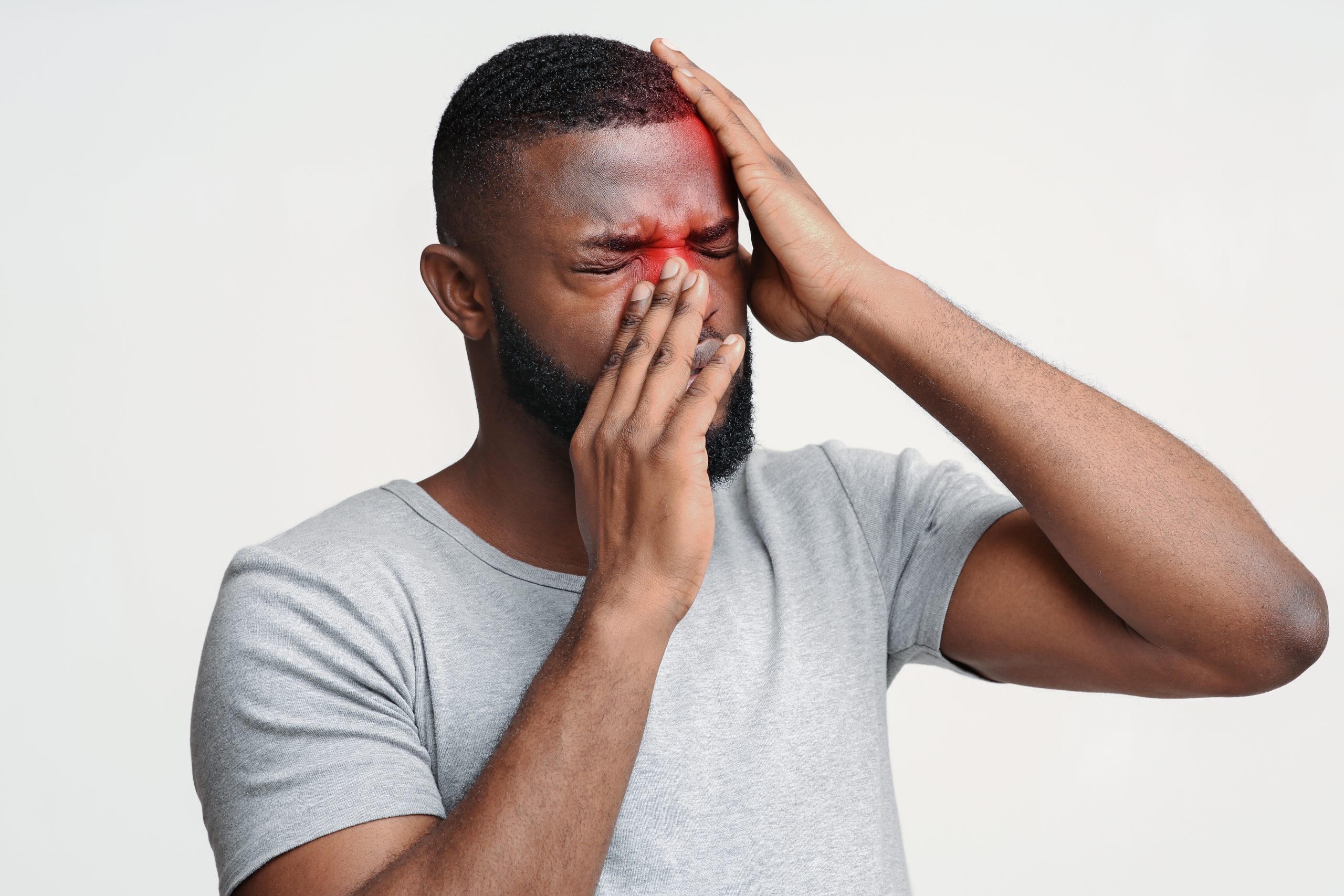 african-american man holding head and nose in sinus pain