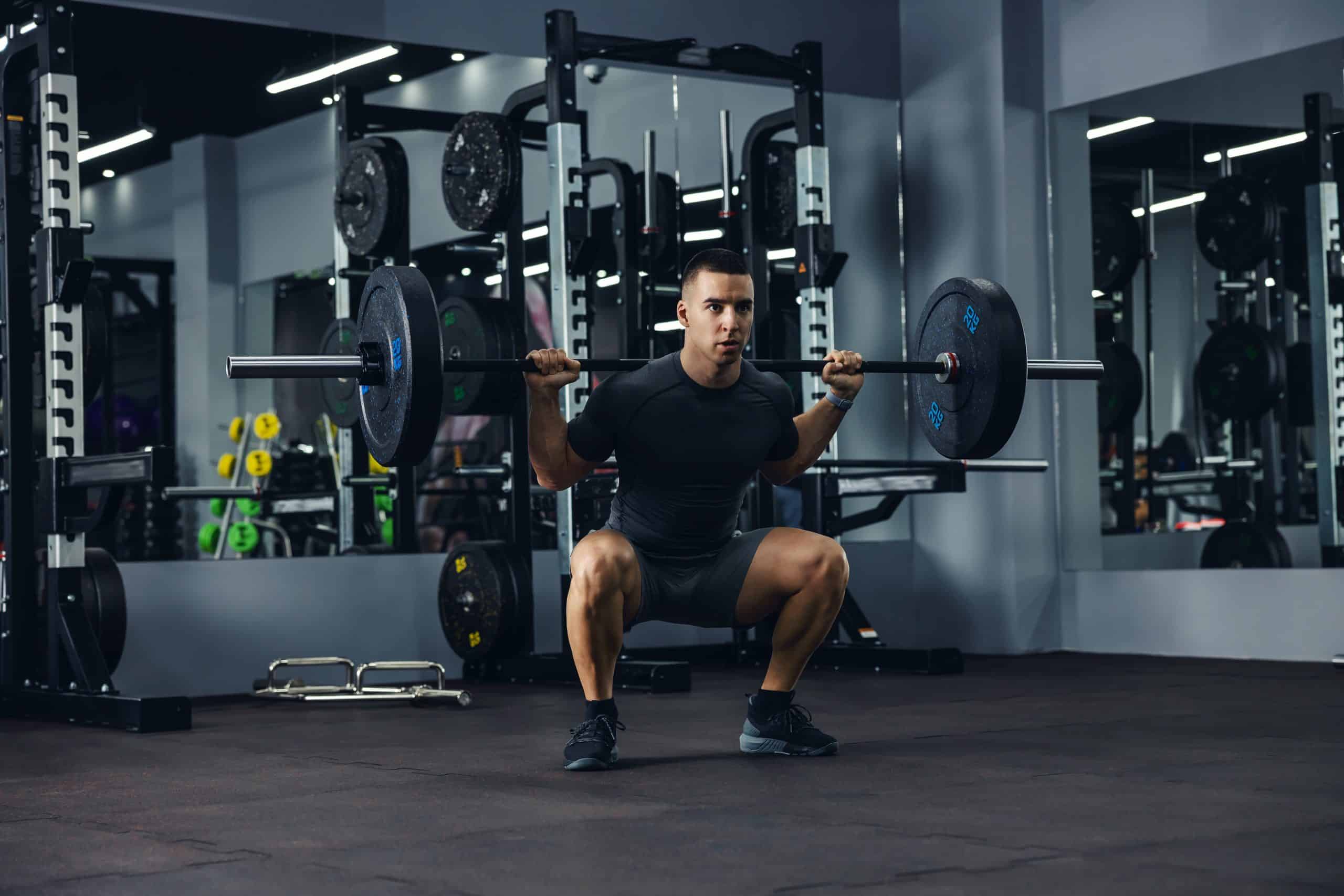 Man squatting with heavy barbells on his shoulders