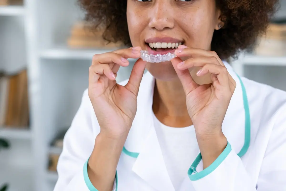 Woman placing a clear dental aligner over her teeth
